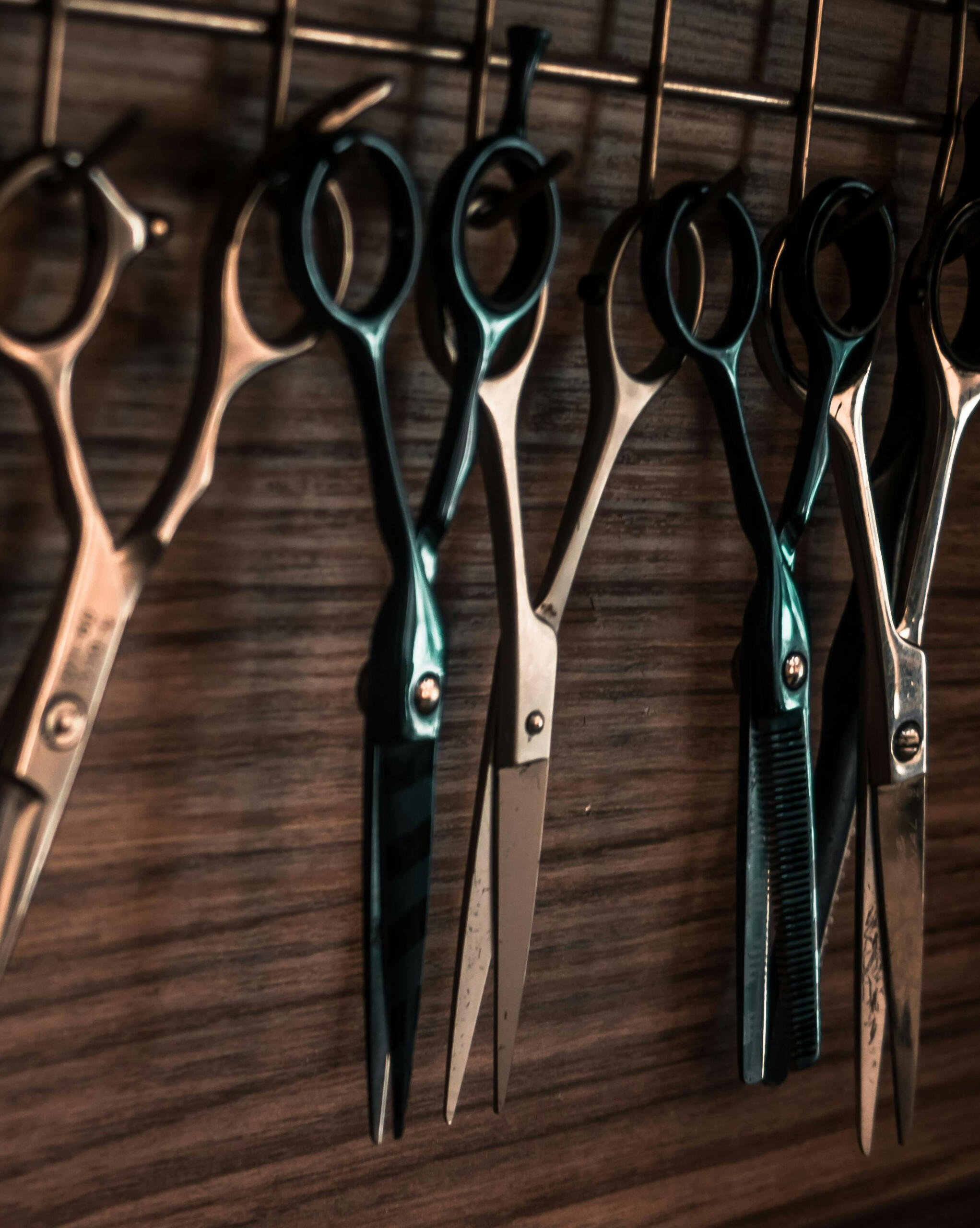 Close-up of professional barber scissors hanging on a wooden wall in a Korean barbershop.