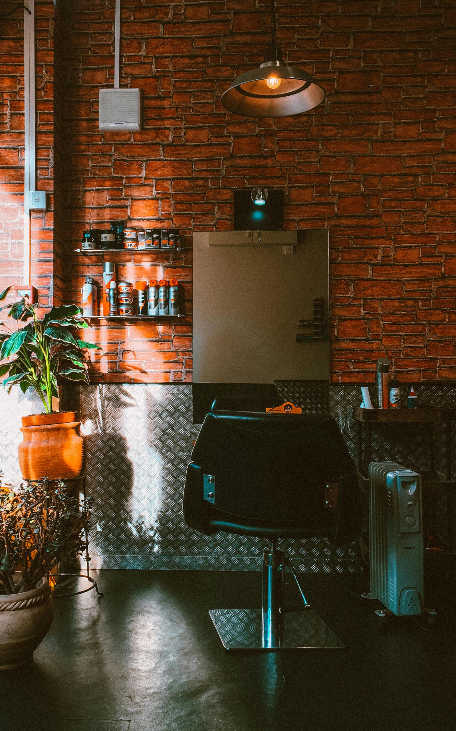 Warm, modern interior of a Seoul barbershop with brick walls, grooming products, and natural lighting.